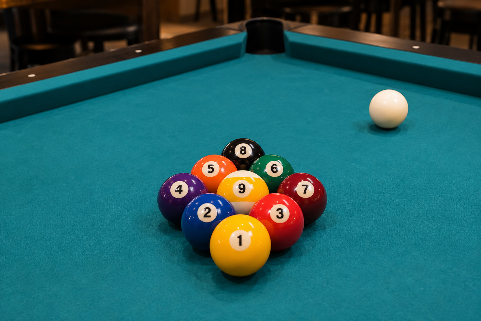 Nine numbered pool balls in a diamond rack with the cue ball apart