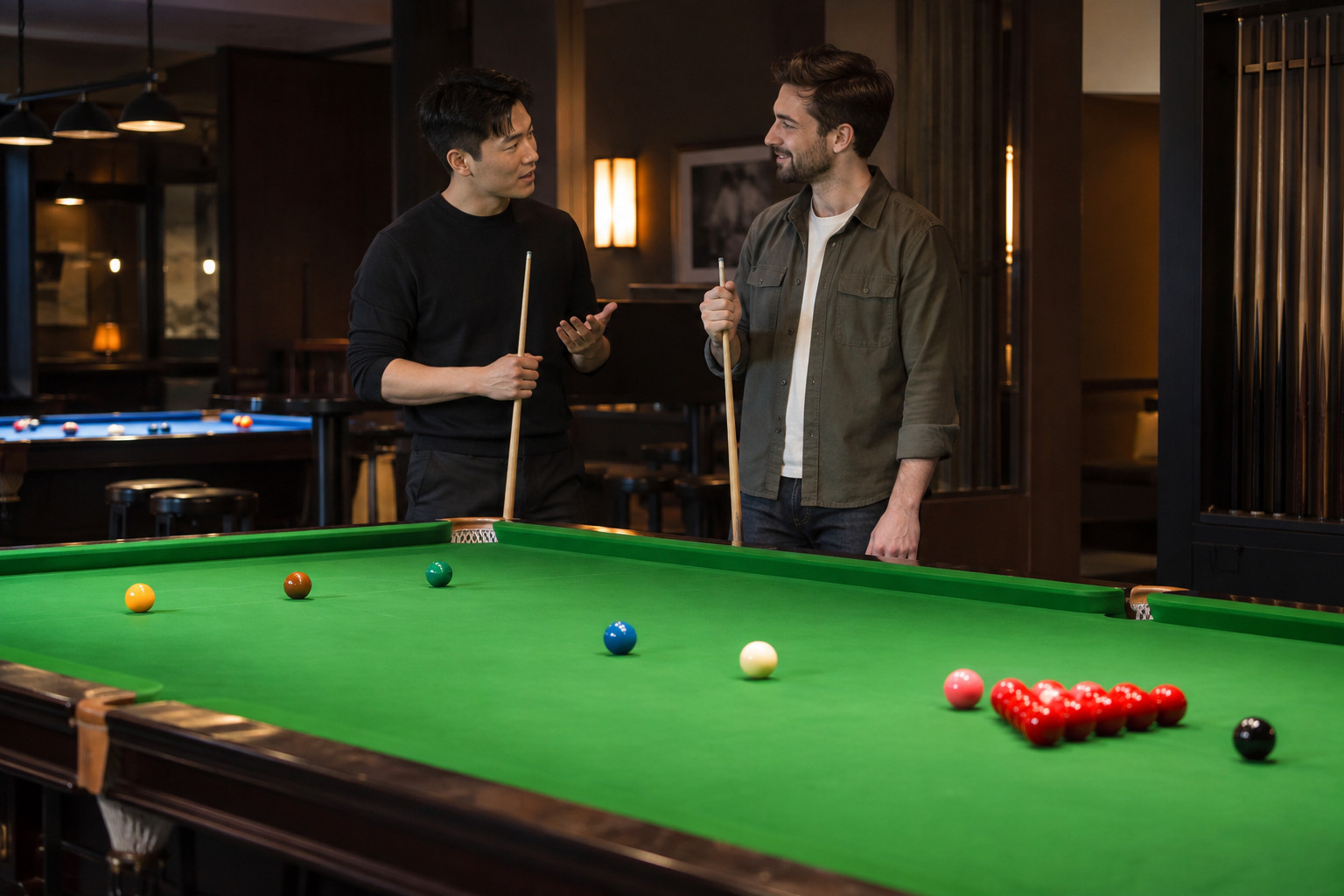 Two friends talking beside a green snooker table